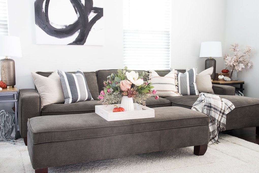 faux floral arrangement for fall on a tray on a couch with blue and neutral throw pillows