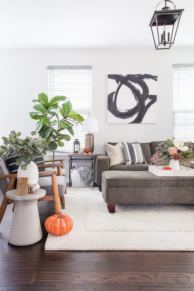 fall living room with blue and neutral throw pillows and orange pumpkin