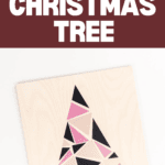 A wooden square board showcases a Modern Geometric Tree Sign with a Christmas tree design crafted from pink, black, and peach triangles. The white background highlights maroon text stating "Modern Geometric Christmas Tree," accompanied by a "Cricut" logo and website link at the bottom.