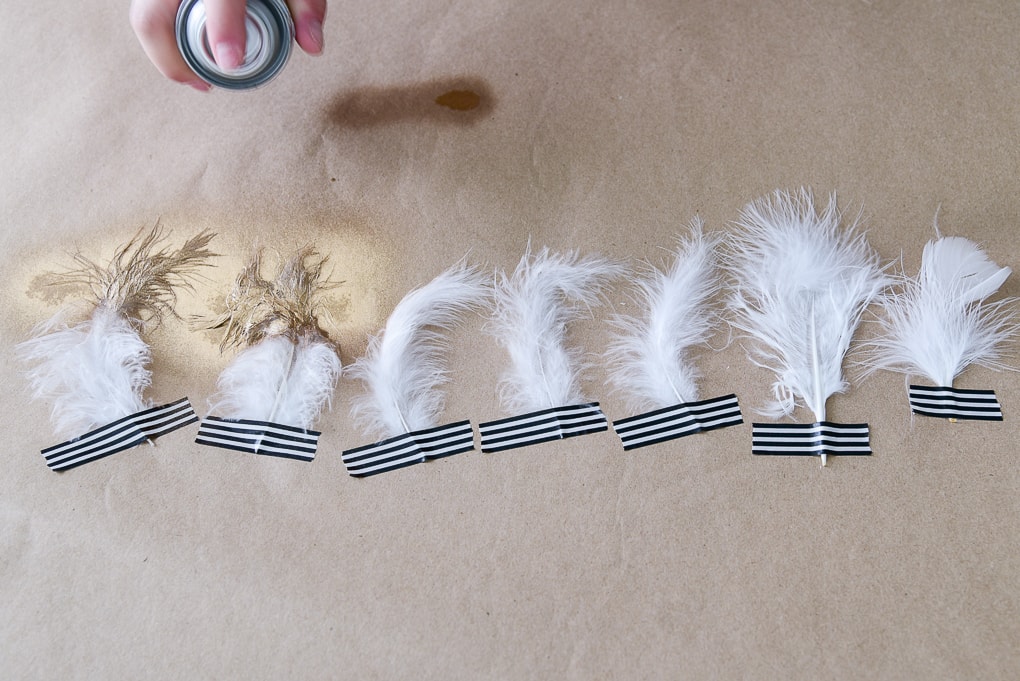 white feathers being spray painted with gold metallic paint