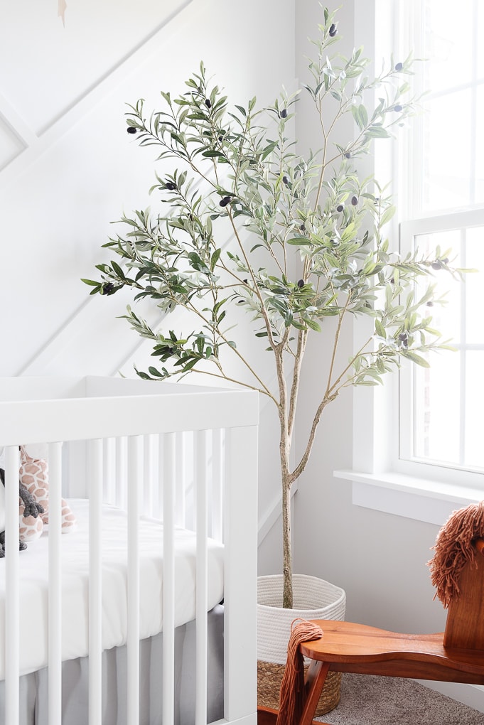 pretty faux olive tree in a basket in a neutral baby nursery