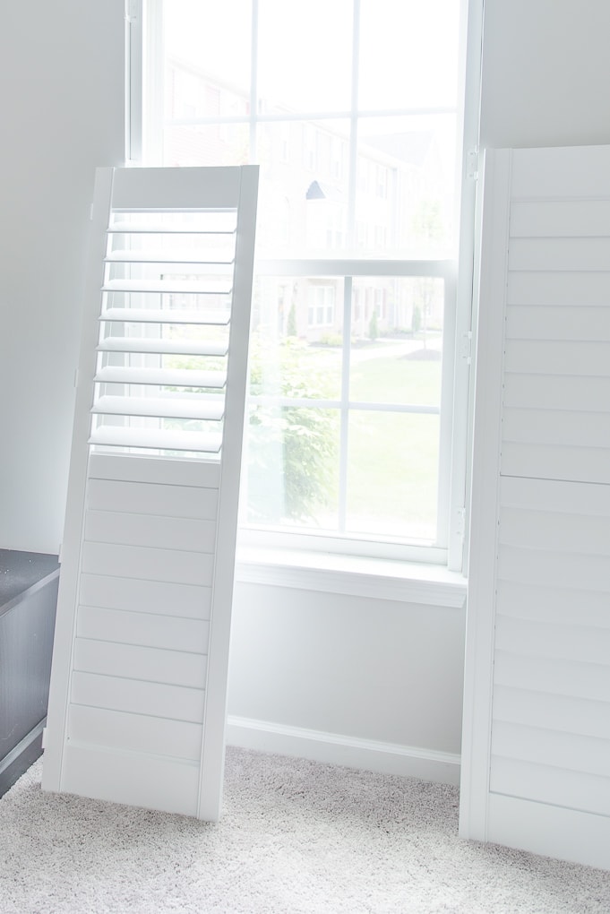 white plantation shutters next to a window before install