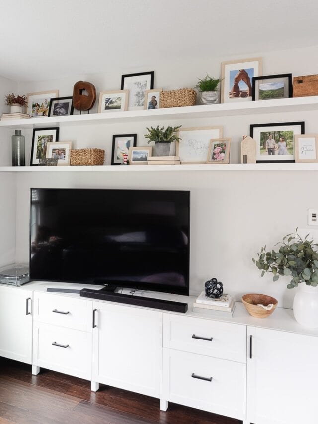 living room media center with floating shelves above the tv decorated with picture frames