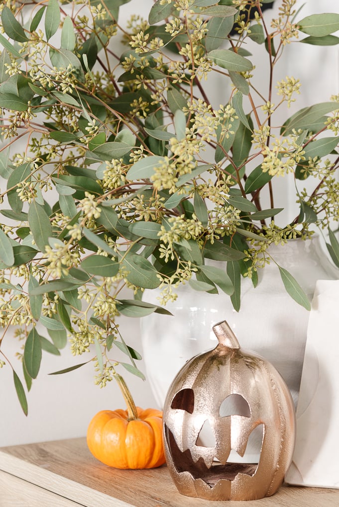 jack-o-lantern with mini orange pumpkin and eucalyptus