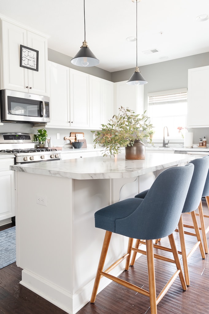 white kitchen with blue counter stools next to island