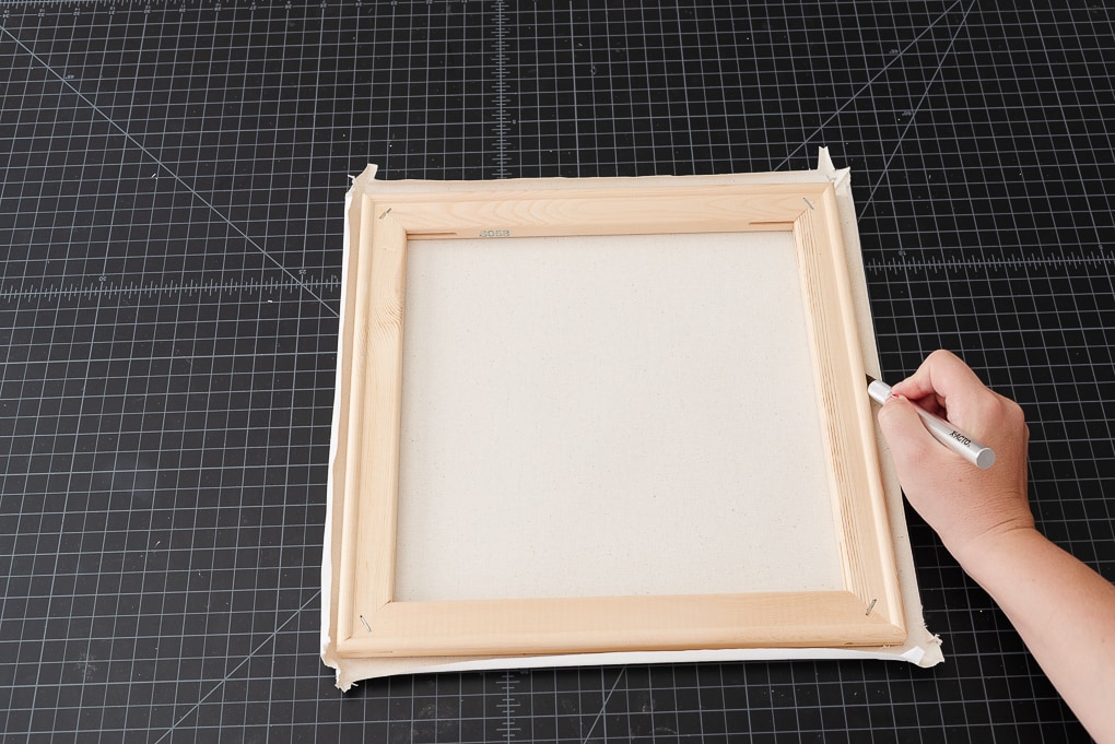 cutting away white canvas to fit behind wooden frame