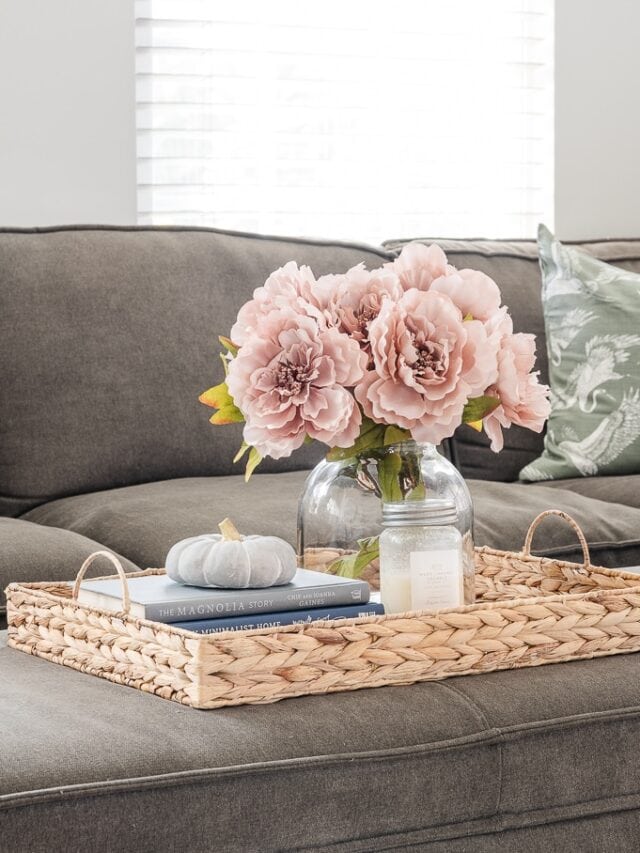 woven tray on ottoman with fall decor and vase with flowers