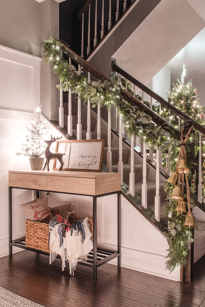 christmas garland at night with twinkle lights and console table with mini tree