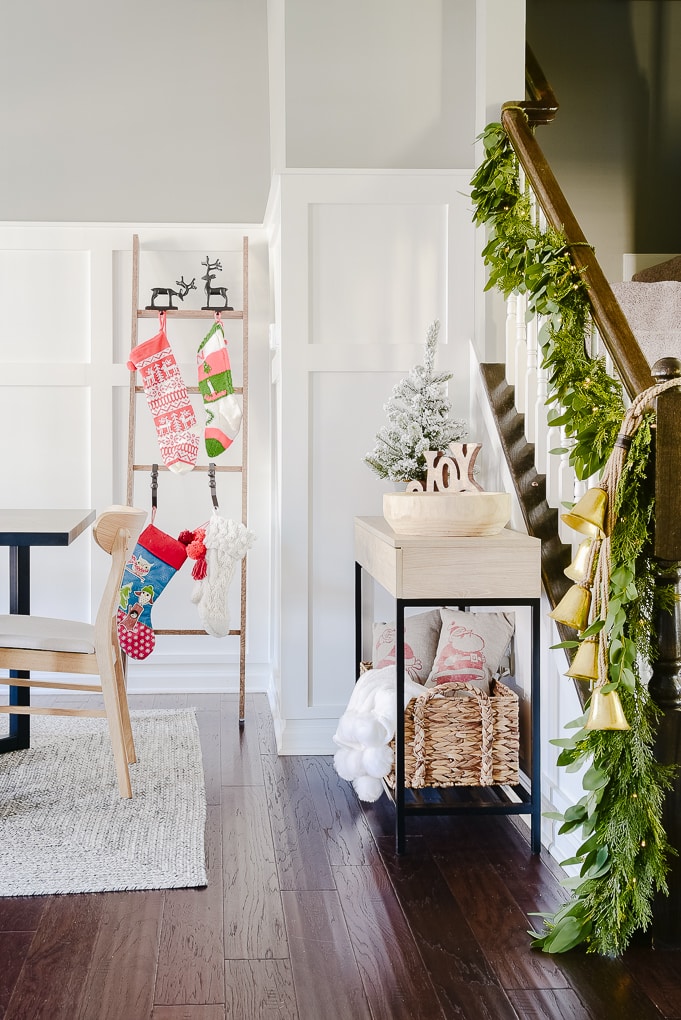 Christmas stocking ladder against white board and batten wall and staircase with Christmas greenery garland