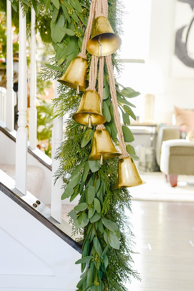 gold bells hanging on staircase at the end of Christmas garland