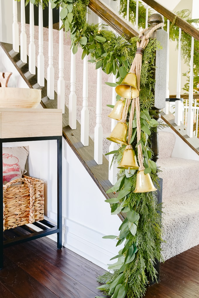 staircase in Christmas dining room with pine and eucalyptus Christmas garland and strand of gold hanging bells