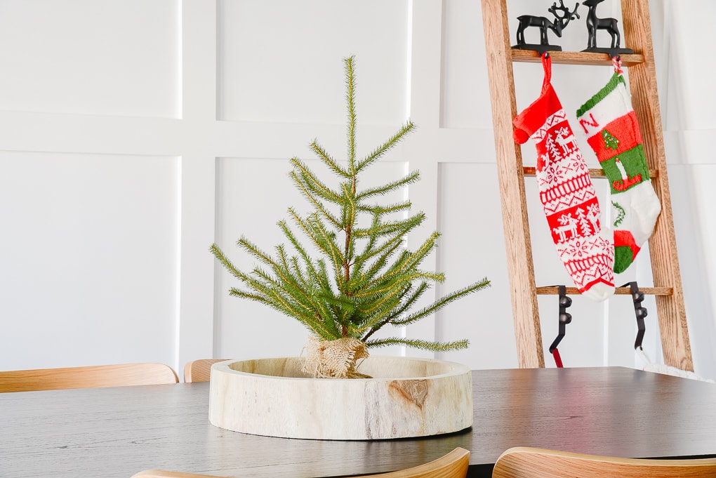 tabletop sparse Christmas tree in wooden round tray in Christmas dining room