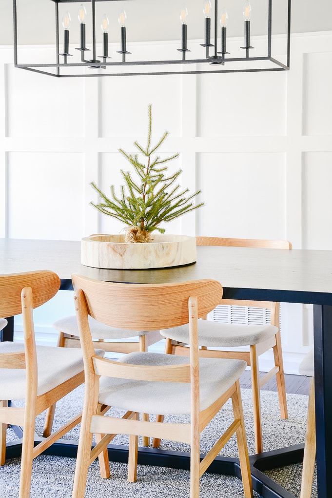 tabletop sparse Christmas tree in wooden round tray on black dining room table