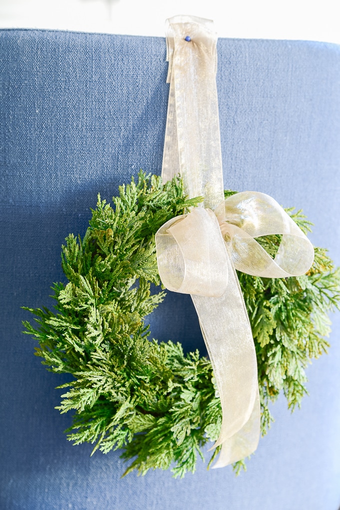 close up of green mini Christmas greenery wreath with bowl attached to blue counter stool