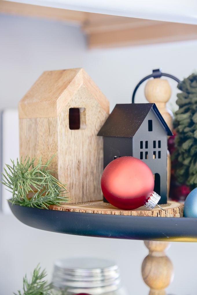 Miniature houses on black metal tiered tray decorated with Christmas ornaments