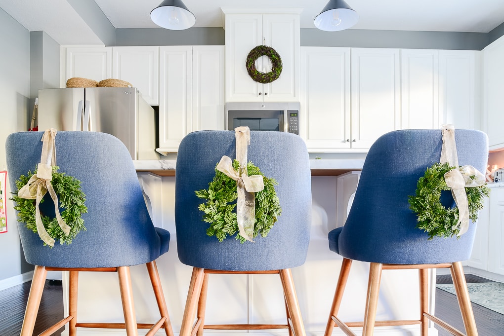 blue kitchen counter stools with mini green christmas wreaths on the back