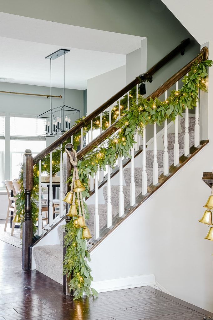 pine and eucalyptus Christmas garland with hanging gold bells on staircase