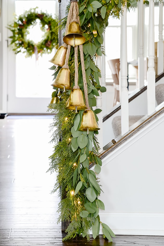 pine and eucalyptus Christmas garland with hanging gold bells on staircase lower section