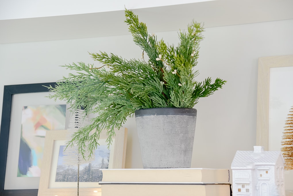 vase of faux Christmas greenery on styled shelves