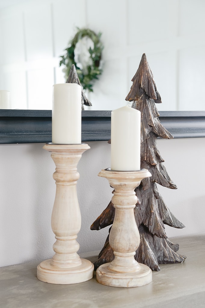 natural wooden pillar candle holders on bookshelf with brown wooden christmas tree figurine