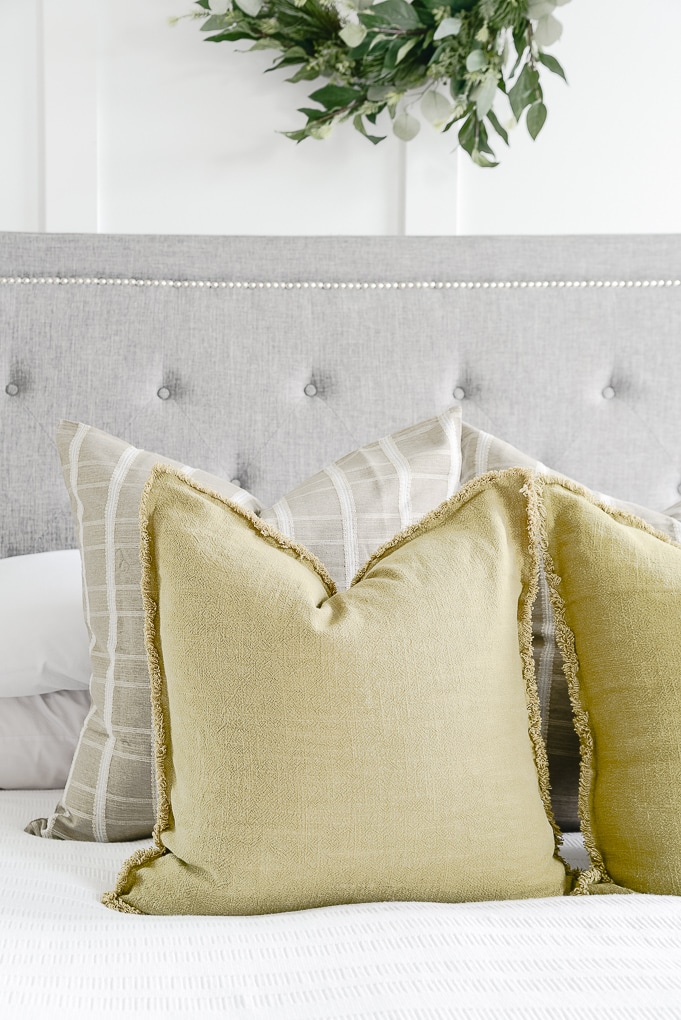 olive green throw pillows on white bedding in master bedroom