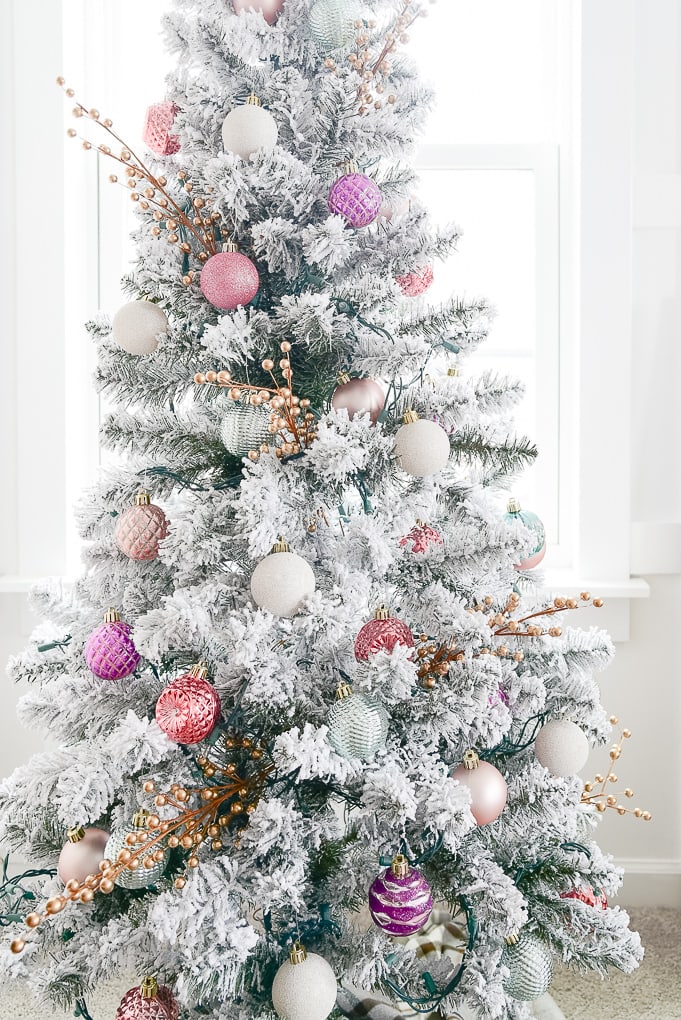 close up of flocked decorated christmas tree with colorful ornaments