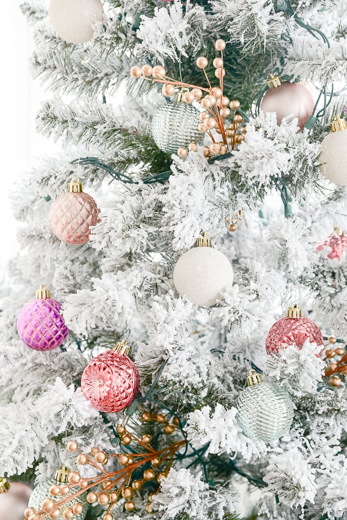 colorful pink and purple ornaments on flocked christmas tree