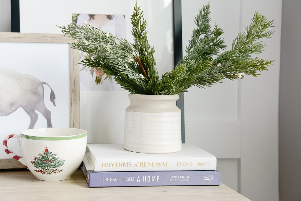 faux christmas greenery inside of a mcgee and co vase and spode christmas mug on nightstand