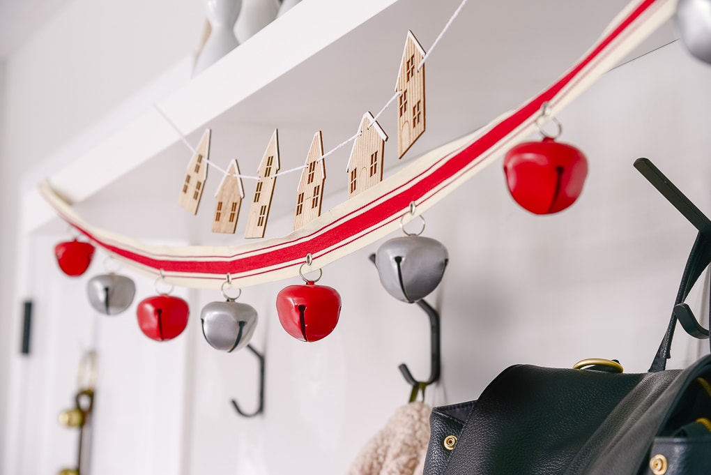 close up of red bell garland hung in a mudroom for christmas