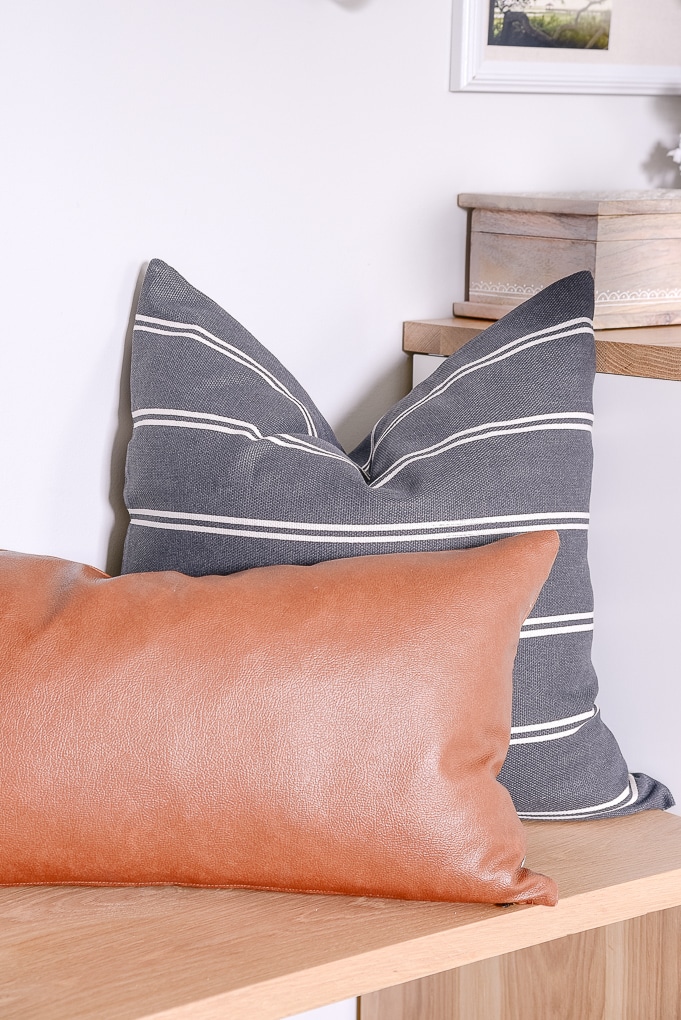 dark gray pillow and leather lumbar pillow on a bench