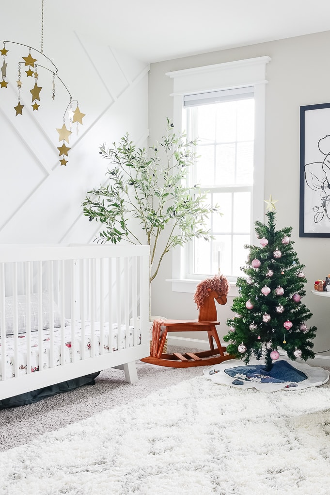 bright white nursery decorated for Christmas with a small multicolor tree