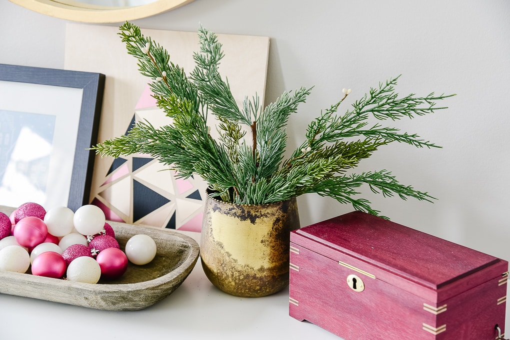 gold vase with christmas greenery on dresser