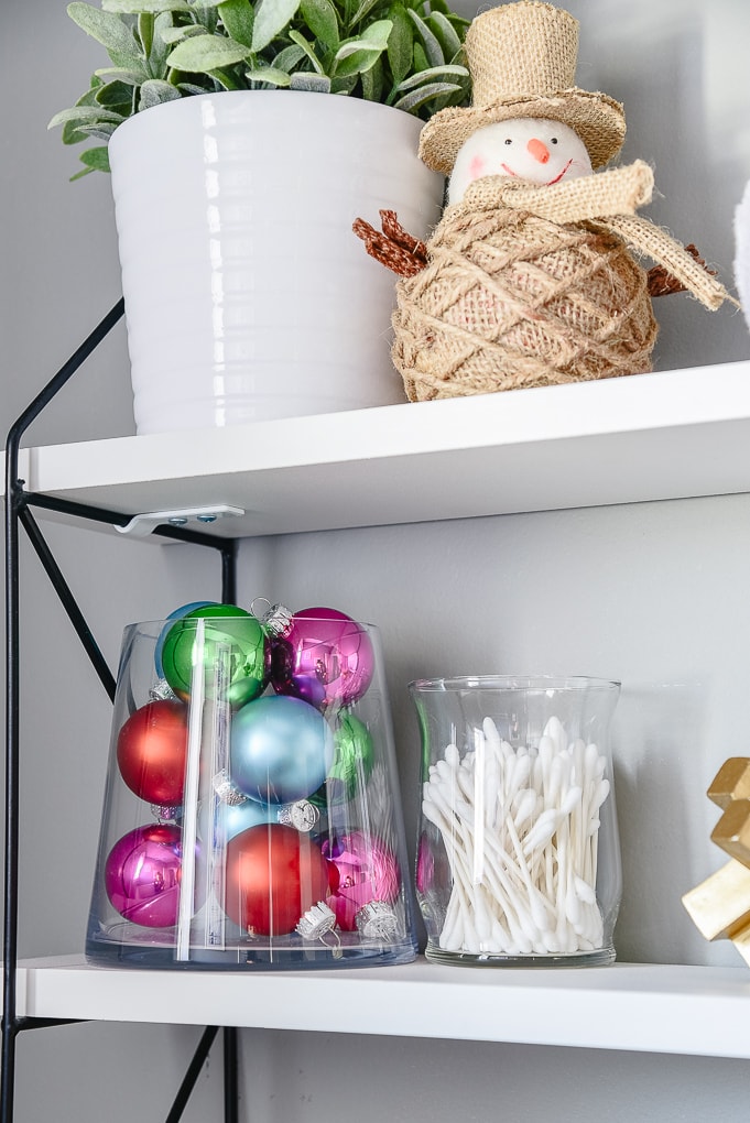 styled shelves in powder room decorated for Christmas with colorful ornaments in a glass jar