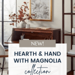 A modern living area featuring wooden furniture, with a desk and shelves. A large window with a black frame lets in natural light. A sign in front reads "New! Hearth & Hand with Magnolia Target Fall Collection" and displays a website URL: CHRISTENEHOLDERHOME.COM.