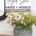 A decorative sign reads "BEST Aged Stone Vases + Vessels" above a textured aged stone vase filled with pink and white flowers. Next to it, there's a small stone bowl. The background includes part of a mirror and a white wall. The website "CHRISTENEHOLDERHOME.COM" is visible.