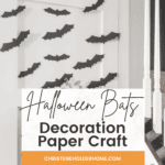 A Halloween-themed room with DIY Halloween bat decor on the wall near a staircase. A wooden table holds a bowl of pumpkins and a metallic pumpkin. Text overlay reads "Halloween Bats Decoration Paper Craft," and there is a website URL at the bottom.