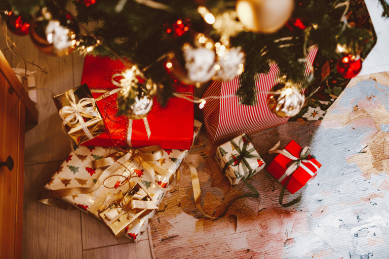 A festive Christmas scene captures wrapped gifts with ribbons and bows under a beautifully decorated tree. Adorned with ornaments and lights, this cozy holiday special is complete with a patterned rug that adds warmth, making it perfect for celebrating family Christmas traditions.